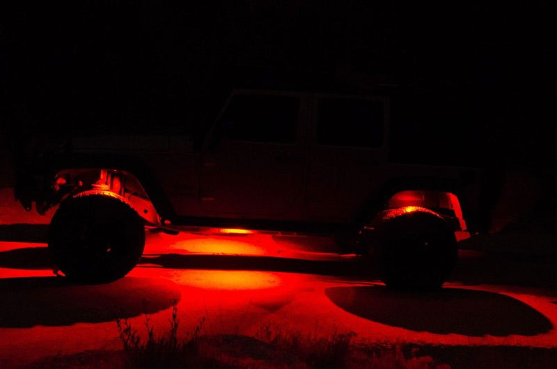 KC HiLiTES C-RGB Multi-Color Rock Light Kit, rock lights glowing red under a Jeep at night