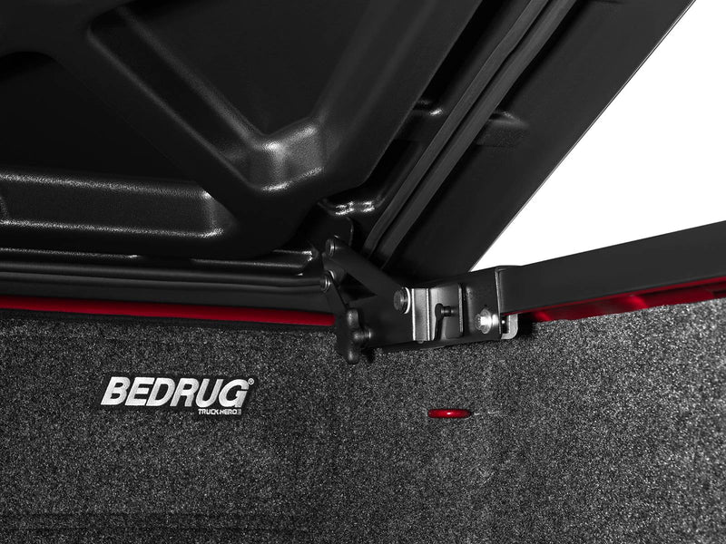 Close-up of the hinge and header bracket where the raised SE lid meets the bed rail.