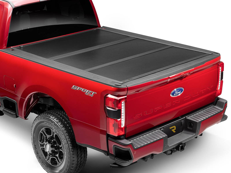 UnderCover Select hard folding tonneau cover closed on a pickup bed, rear three-quarter view, matte-black panels flush with the bed rails.