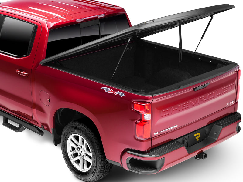 UnderCover SE one-piece tonneau cover raised on its struts, rear three-quarter view, the lined bed floor open to the camera.