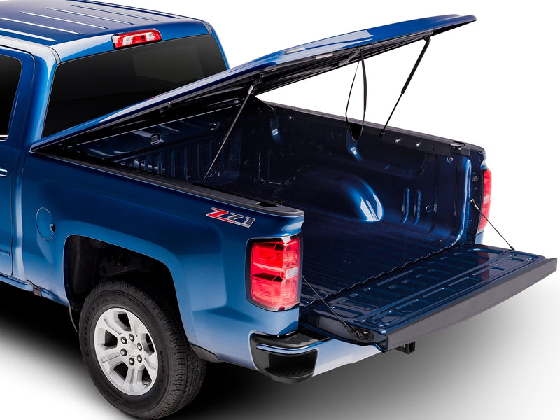 UnderCover LUX one-piece tonneau cover raised on its strut with the tailgate down, rear three-quarter view looking the full depth of the open bed.