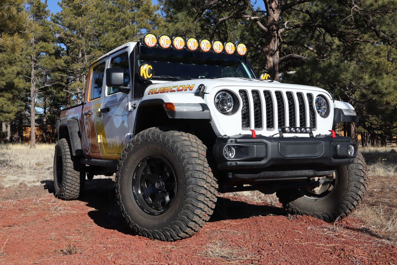KC HiLiTES 6" Round Light Cover & Shield, Jeep Wrangler on a dirt trail with KC soft covers on its lights