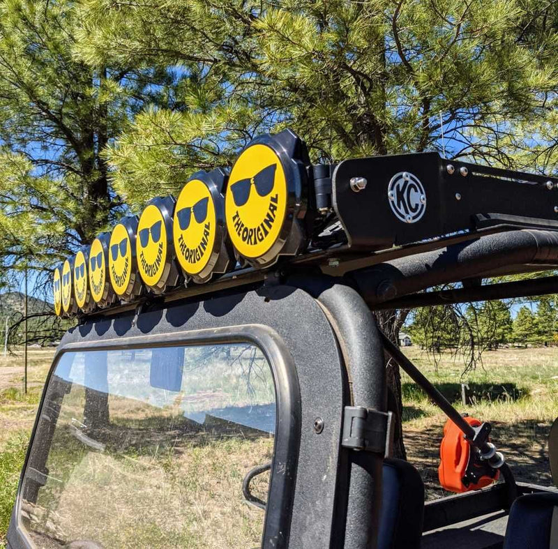 KC HiLiTES Gravity Titan & Pro6 6" Light Cover & Shield, smiley face covers on a row of lights over a Jeep windshield