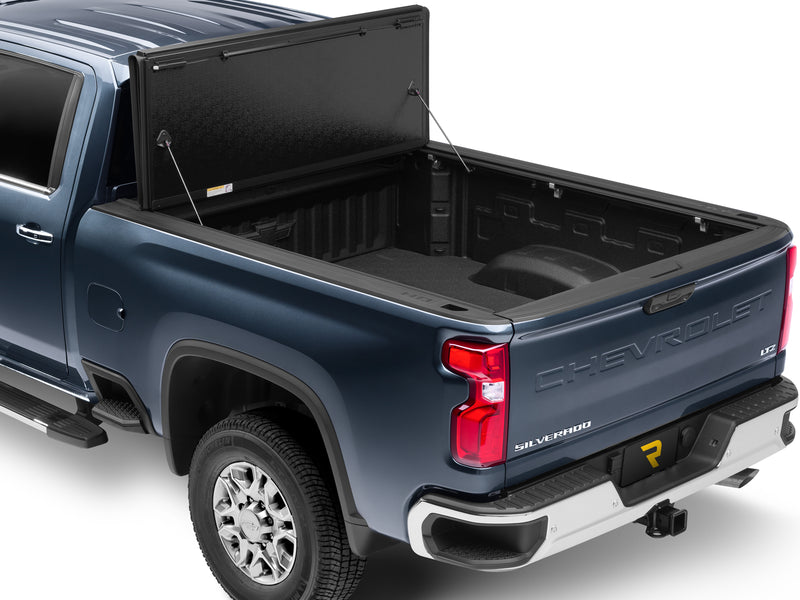 UnderCover Flex hard folding tonneau cover folded fully open and stacked at the bulkhead with the tailgate closed, the whole bed floor visible over the tailgate, rear three-quarter view.