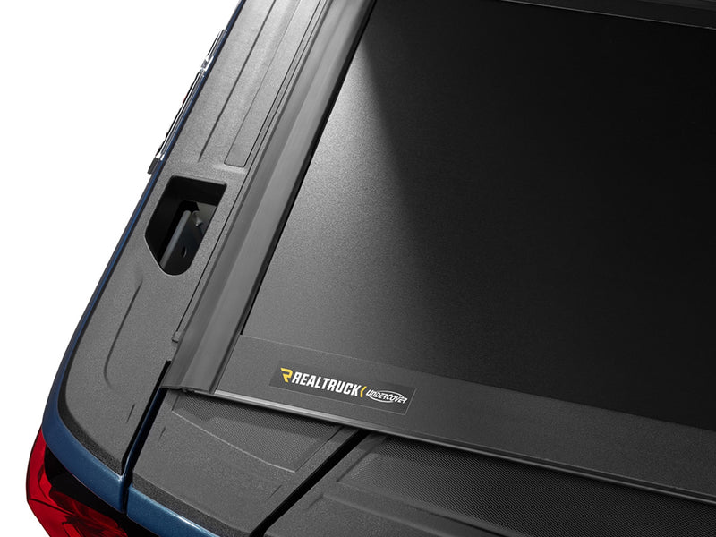 Close-up of the RealTruck UnderCover nameplate on the matte-black rear panel of the Select cover.