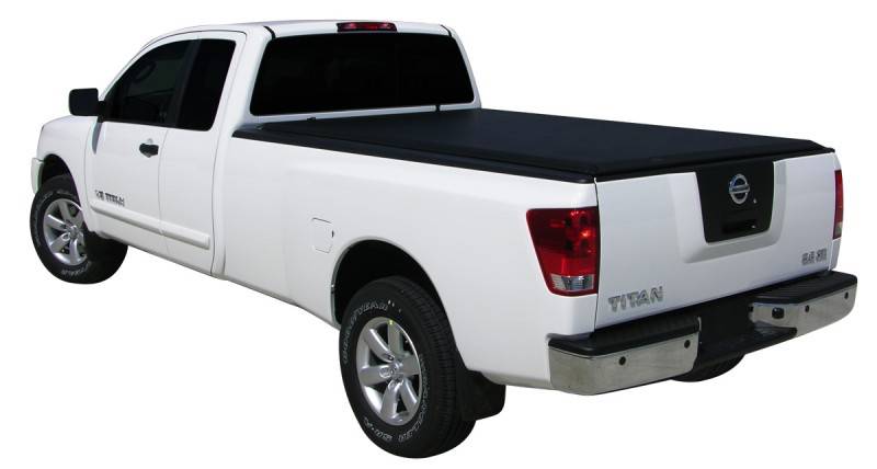 Rear three-quarter studio view of a white extended cab long-bed pickup with the black roll-up cover closed