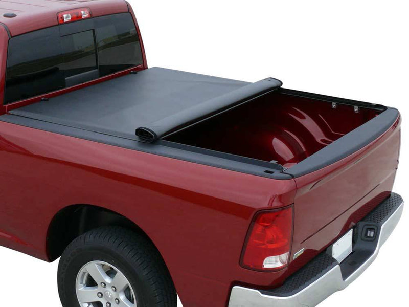 Black roll-up tonneau cover partly rolled toward the cab on a red pickup, rear half of the bed open, white background