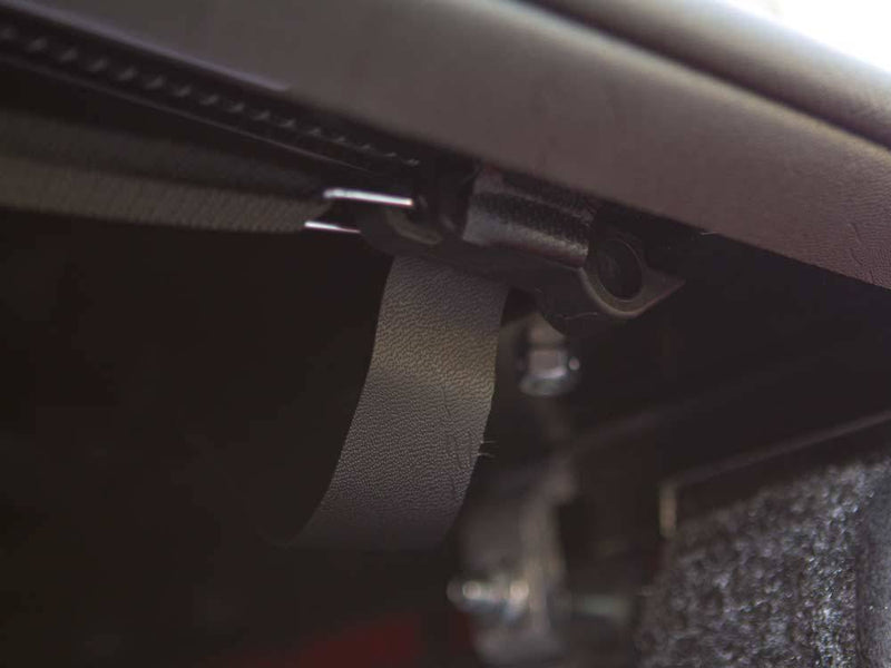 Underside of the side rail with a black strap hanging below the rolled cover