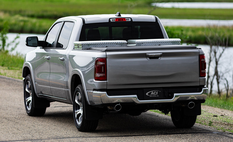 Access Toolbox Edition roll-up tonneau cover on a pickup bed: rear view of a silver pickup on a road, black roll-up cover closed behind an aluminum diamond-plate bed toolbox (truck-bed toolbox shown, not included)