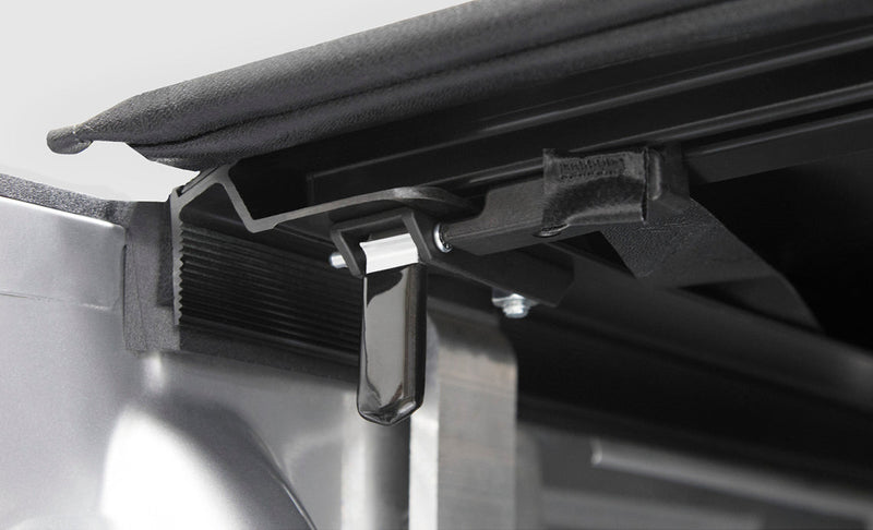 Studio close-up of the trigger latch under the rear rail of the cover
