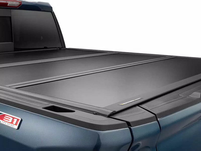Close rear three-quarter of the Select cover closed and flush, showing the panel seams, the rear bed rail and the RealTruck UnderCover nameplate.