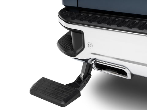 BedStep deployed under a white rear bumper, showing the step pad and swing-arm linkage