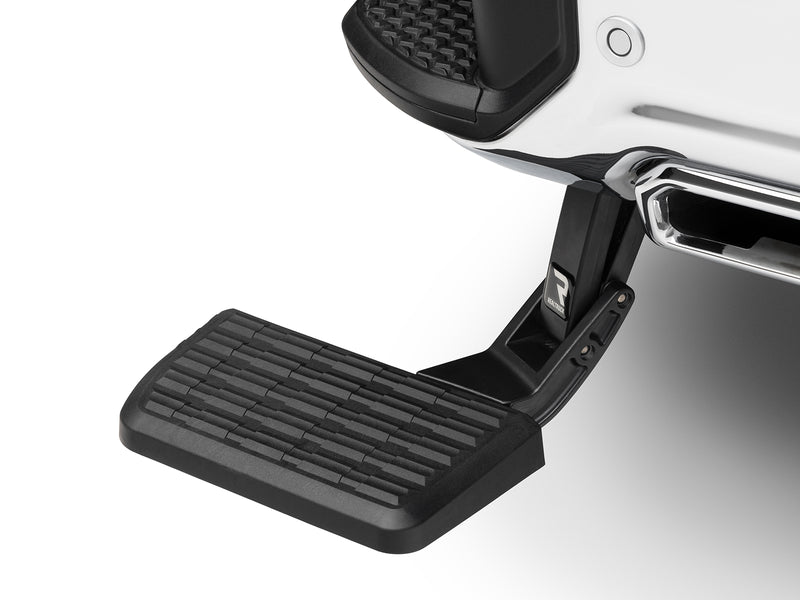 BedStep deployed below a white rear bumper beside a chrome exhaust tip, studio background