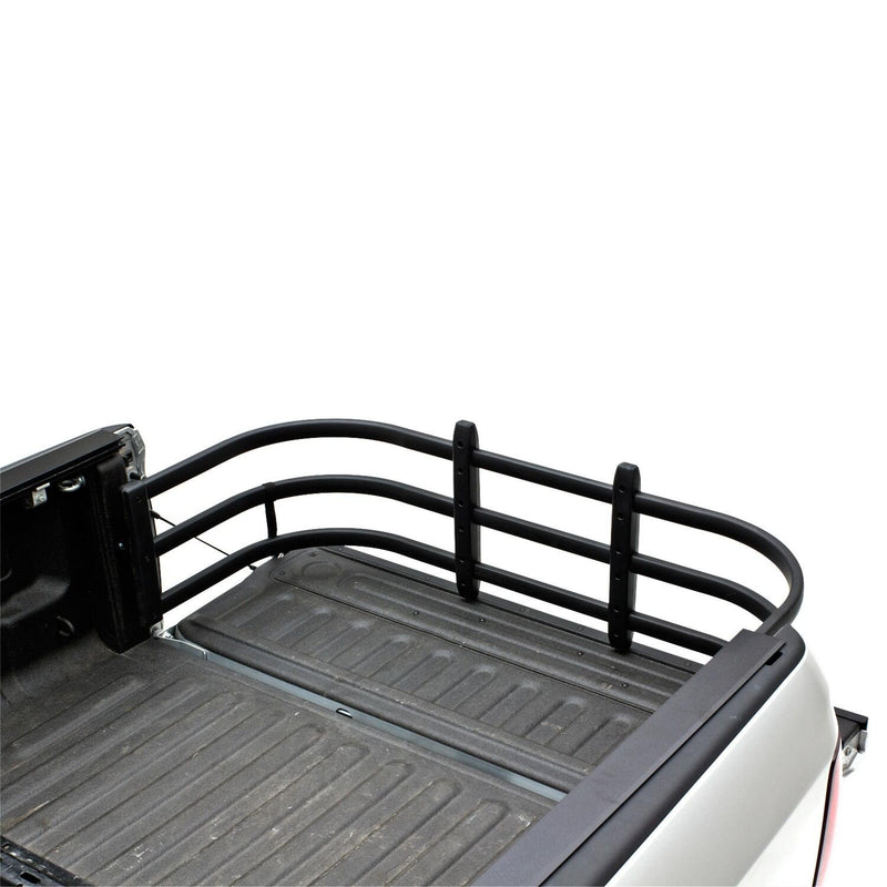 Black bed extender extended over the lowered tailgate of a silver pickup, high rear view