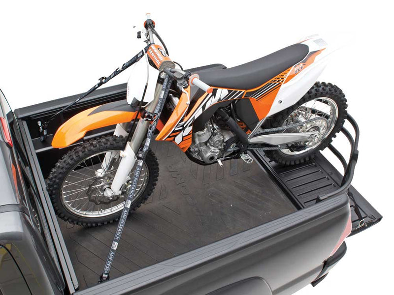 A dirt bike strapped into a gray pickup bed with its rear wheel resting inside the extended BedXTender HD Moto