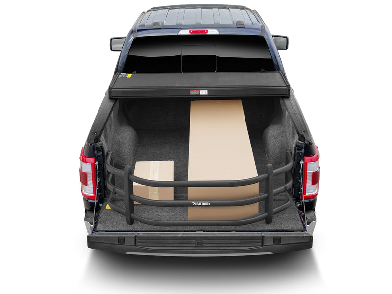 Rear view of a pickup with the BedXTender HD Sport extended, holding a long board and a box