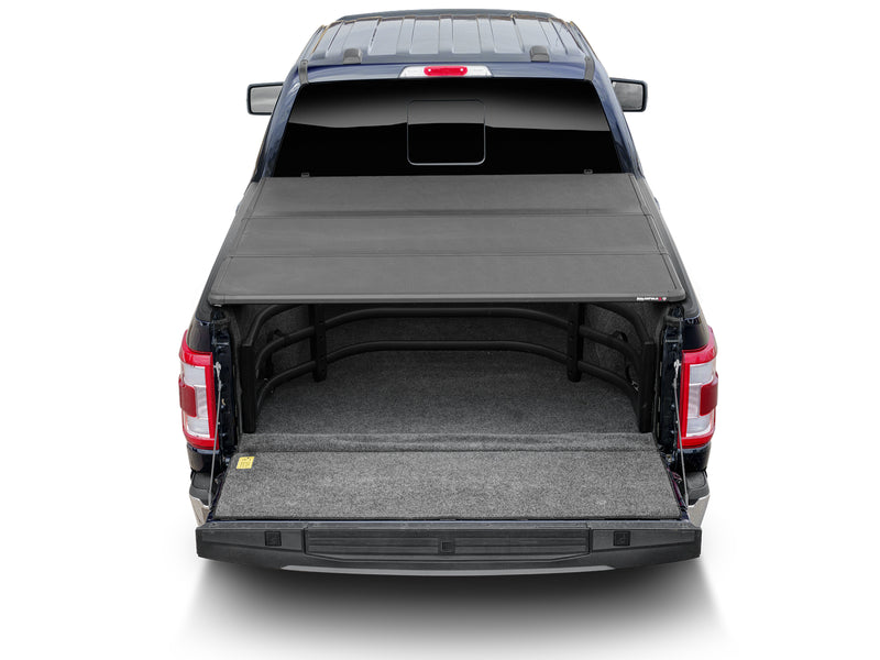 Rear view of a pickup with the BedXTender HD Sport stowed under a partly closed hard cover