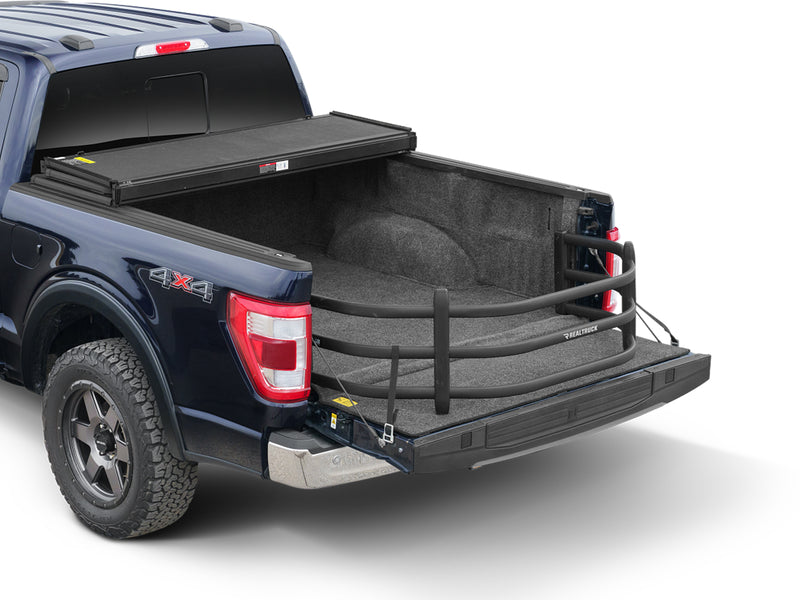 Dark blue pickup with the BedXTender HD Sport extended over the lowered tailgate, rear three-quarter studio view