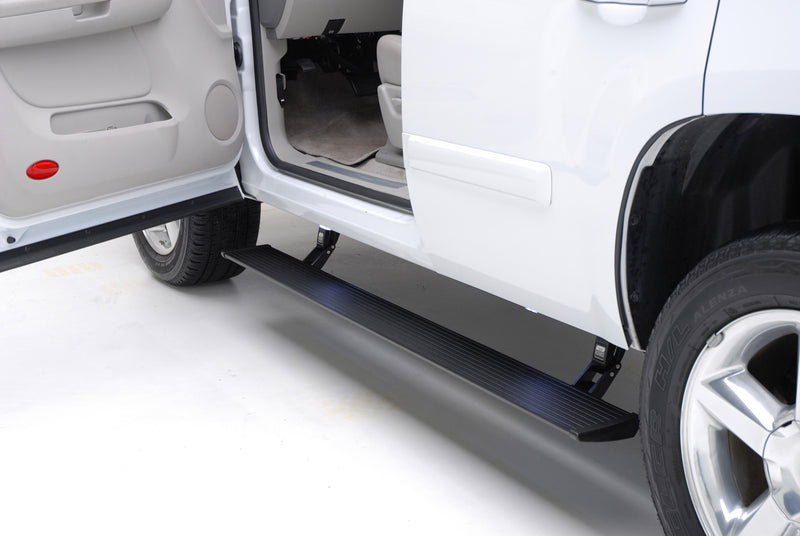 Running board deployed under the open rear door of a white pickup, studio