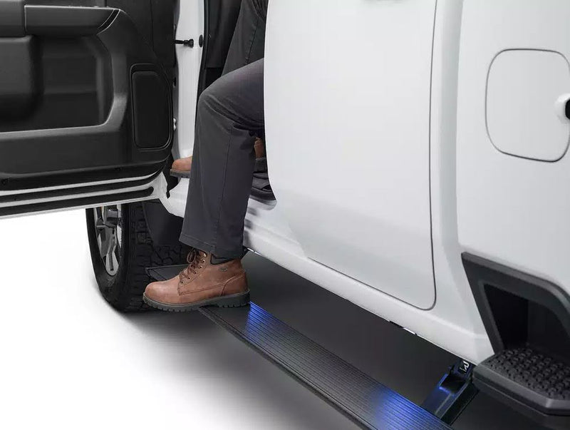 A boot on the lit running board as a person climbs into a white pickup with the door open