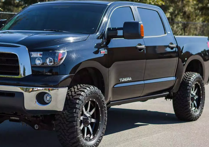 Lifted black crew-cab pickup parked outdoors with the running board stowed