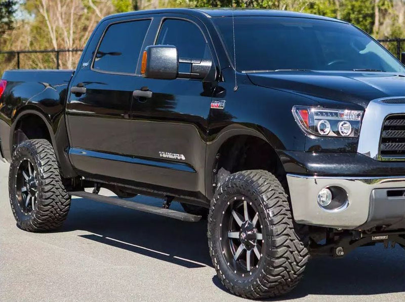 Lifted black crew-cab pickup parked outdoors with the running board stowed, second angle
