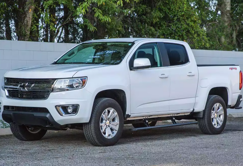 White mid-size crew-cab pickup parked on asphalt, running board under the doors
