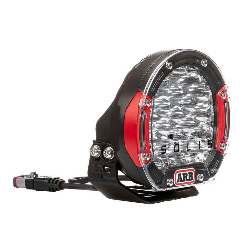 ARB Intensity SOLIS LED driving light with red bezel inserts and mounting bracket, front three-quarter view on white