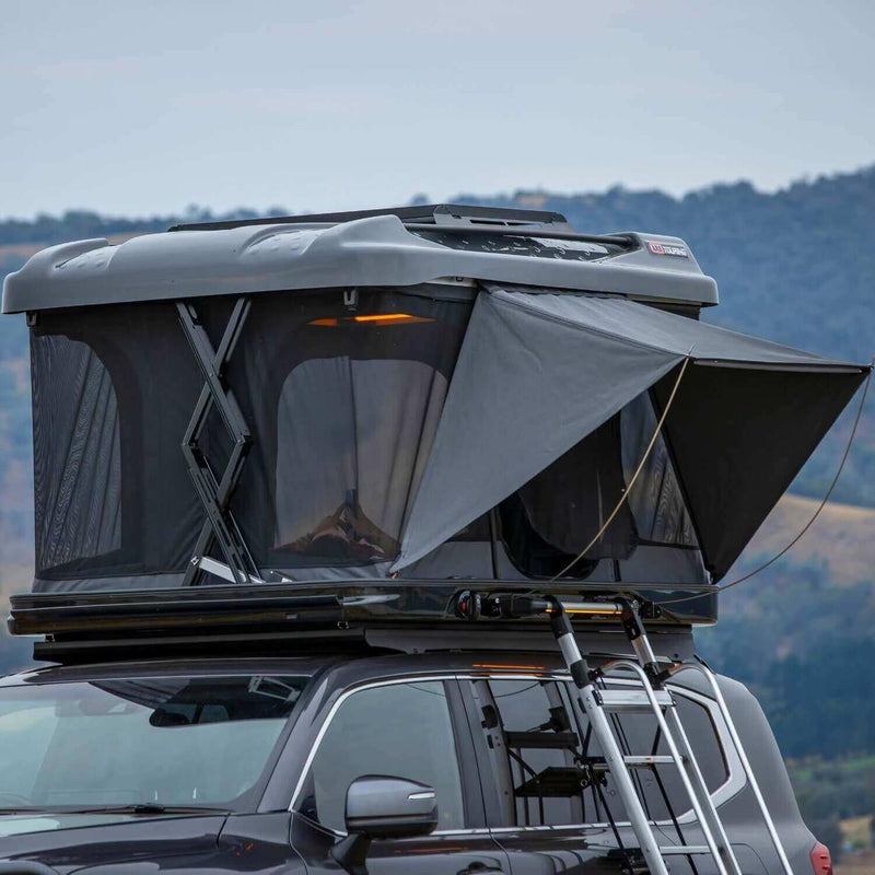 ARB Altitude hardshell rooftop tent raised on a roof rack with lake and hills behind