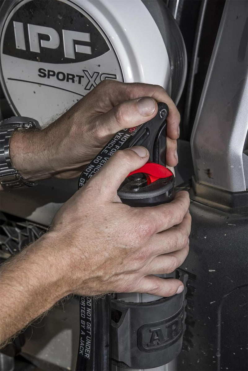 Hands releasing the ARB JACK from its vehicle mount