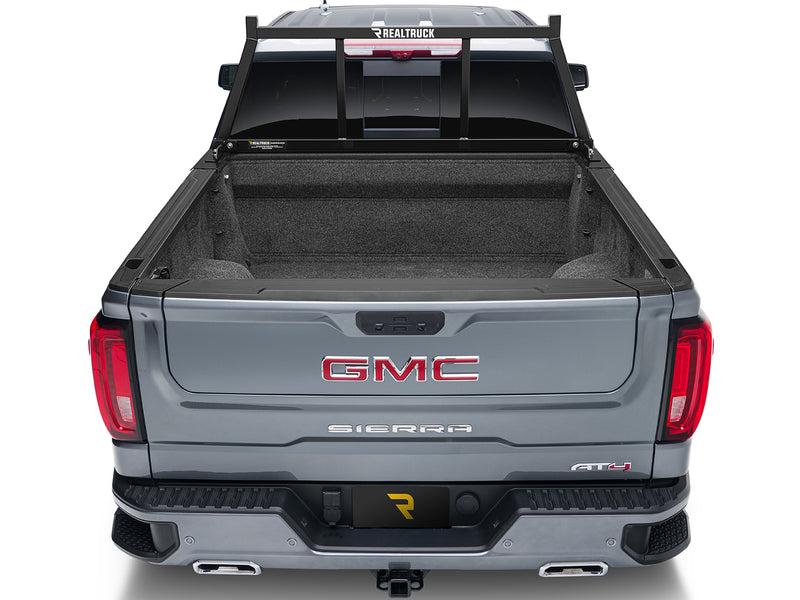 BackRack Open: rear view of a gray pickup with a black open headache rack mounted behind the cab and an empty carpeted bed