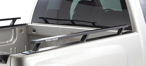 BackRack Side Rails: A black bed side rail with three stake-pocket legs runs along the top of a white pickup bed, with the matching rail visible on the far side