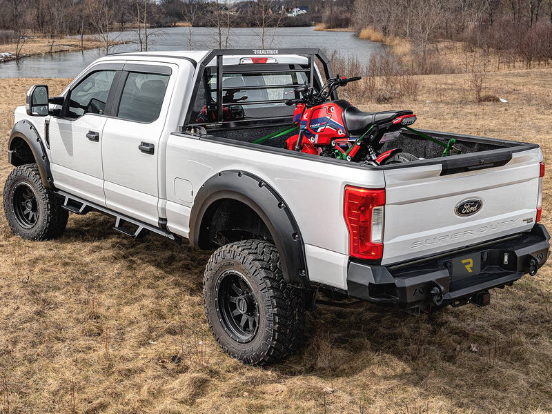 BackRack SR: A white Ford Super Duty with a black SR headache rack hauls a red minibike outdoors by a lake
