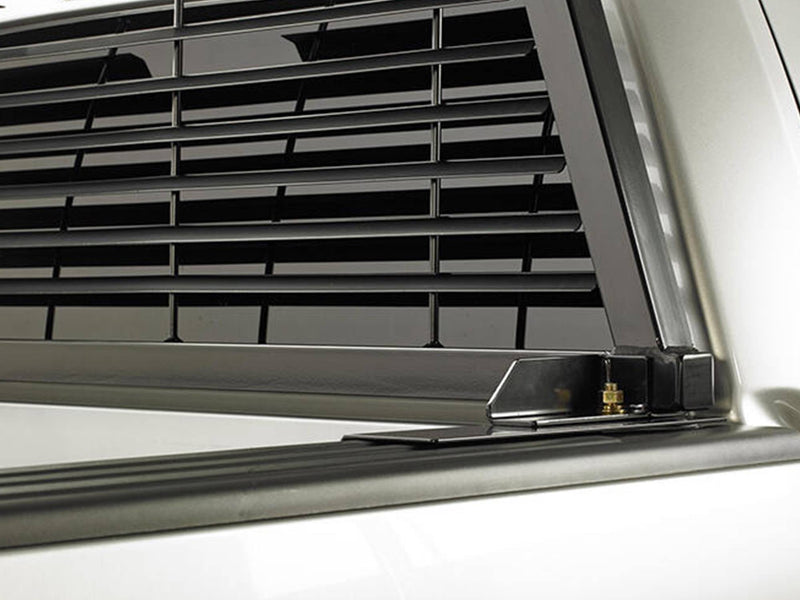 BackRack Standard: black standard mounting bracket bolted to a silver bed rail beneath a louvered headache rack