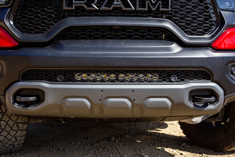Baja Designs OnX6+ 20" Bumper Light Bar Kit on a Ram 1500 TRX: A light bar mounted low in the grille above the front bumper of a gray Ram pickup