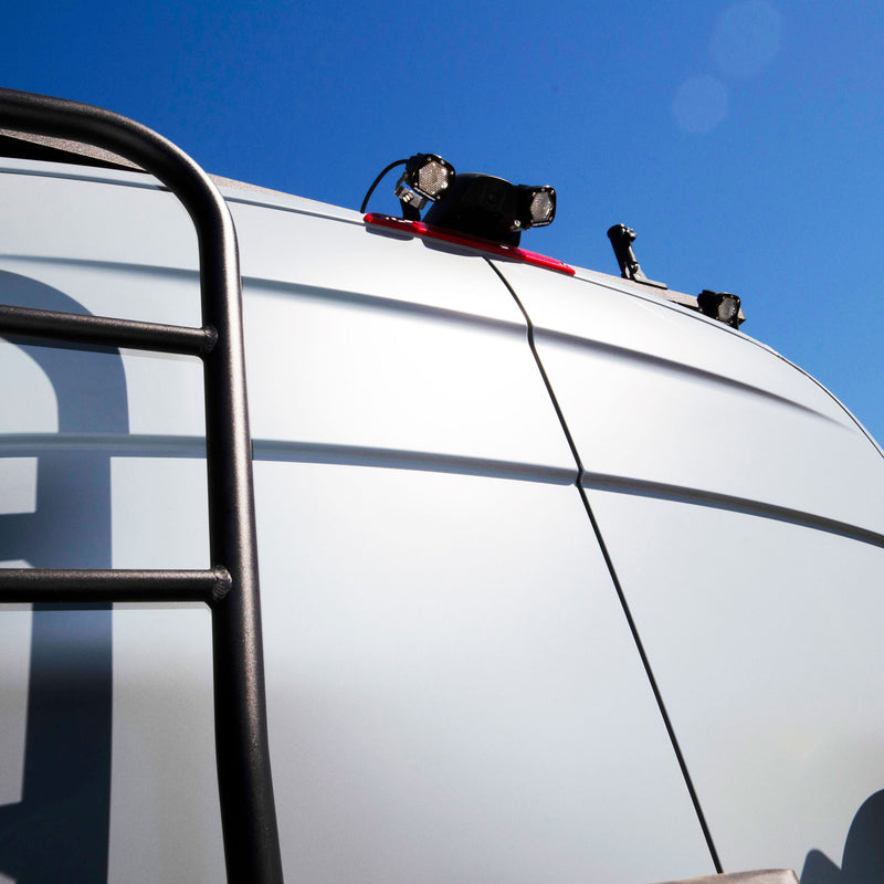 Baja Designs S1 Dual Reverse Light Kit on a vehicle: two S1 pods mounted above the third brake light on the roof of a white van beside a rear ladder