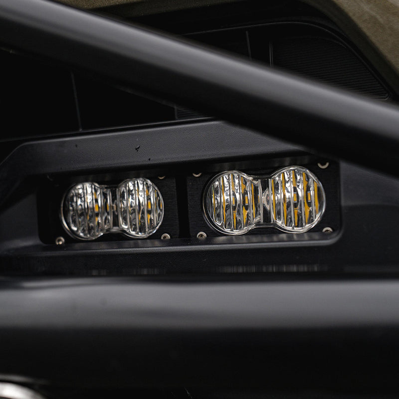 Baja Designs S2 Sport OEM Fog Light Replacement Kit on a vehicle: close view of two clear S2 fog lights mounted side by side in a black lower bumper opening