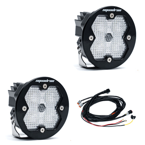 Baja Designs Squadron-R 2.0 Sport Black LED Auxiliary Light Pod Pair, whole product on a studio background: A pair of round black Squadron-R LED pods with clear diffused lenses and a wiring harness on a white background