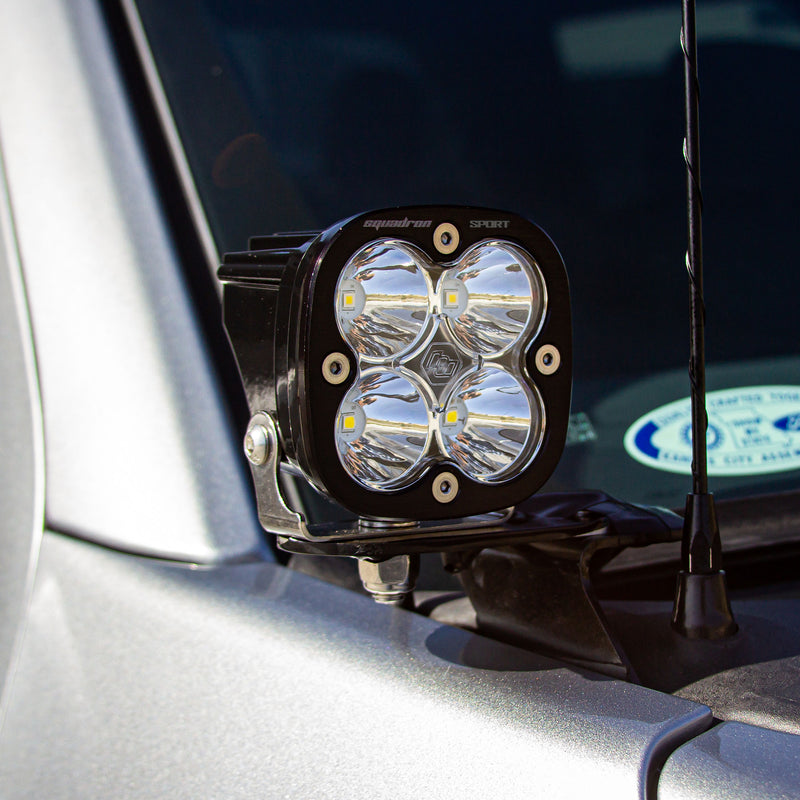 Baja Designs Squadron Sport A-Pillar Light Kit on a vehicle: A Squadron Sport LED pod with a clear lens on an A-pillar bracket of a silver truck beside the antenna