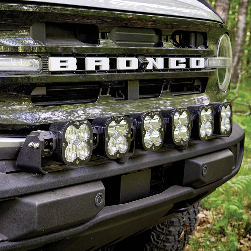 Baja Designs XL Linkable Bumper Light Kit on a Ford Bronco: close angled view of six linkable LED pods mounted on the front bumper below the Bronco grille lettering
