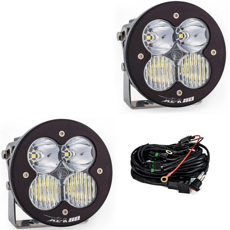 Baja Designs XL-R 80 LED Auxiliary Light Pod Pair, whole product on a studio background: A pair of Baja Designs round XL-R 80 pods with clear lenses shown on a white background beside the wiring harness