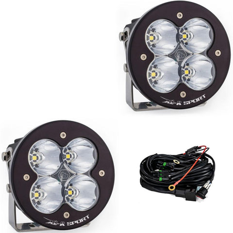 Baja Designs XL-R Sport LED Auxiliary Light Pod Pair, whole product on a studio background: A pair of black round Baja Designs XL-R Sport LED light pods with clear spot lenses and a wiring harness, shown on white