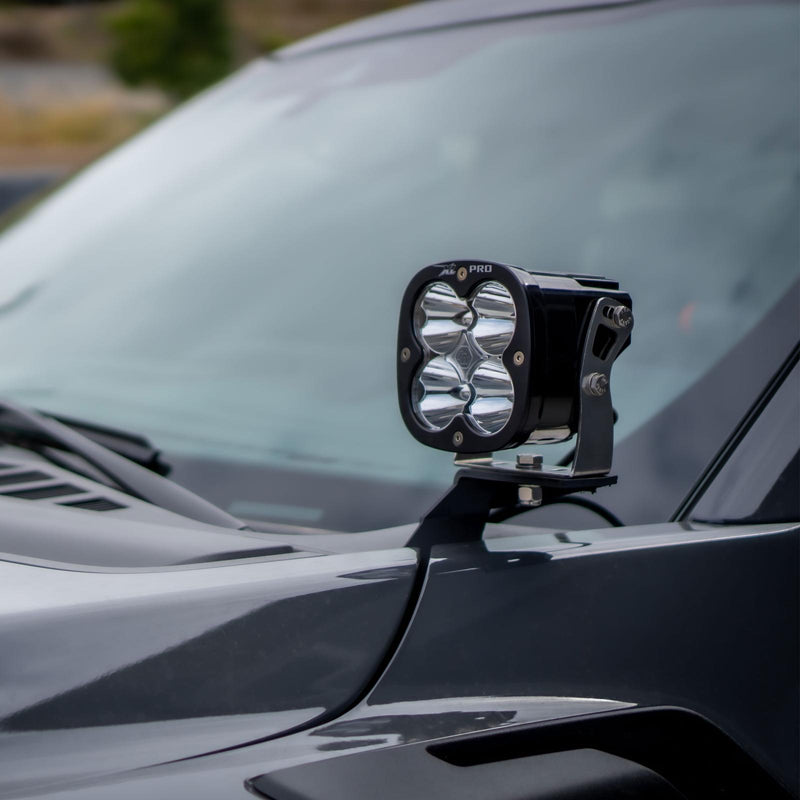 Baja Designs XL80 A-Pillar Light Kit on a vehicle: A Baja Designs XL series (badge not legible) LED pod mounted on an A-pillar bracket beside the windshield of a dark gray truck