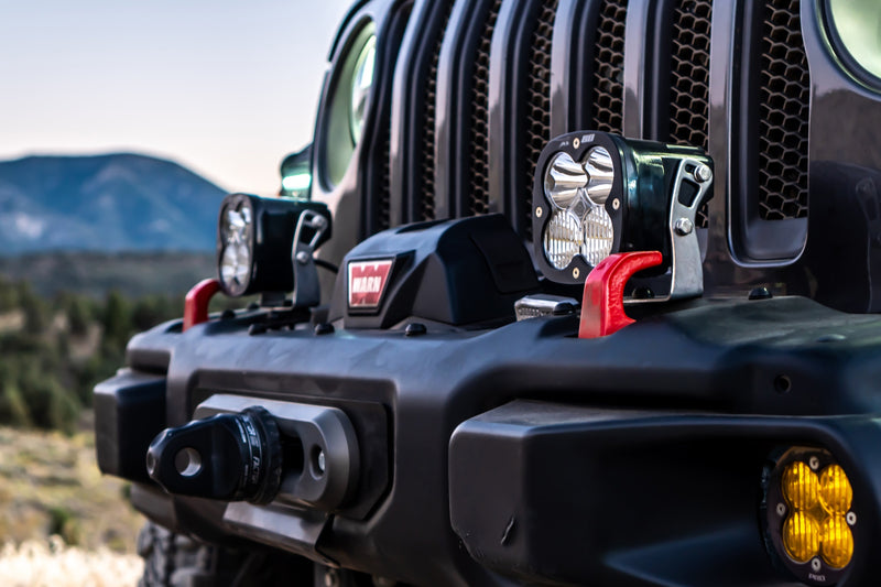 Baja Designs XL80 Bumper Light Kit on a Jeep Wrangler JL / Gladiator JT: two square XL pods mounted on a black Jeep JL steel bumper next to a winch, with an amber fog light below