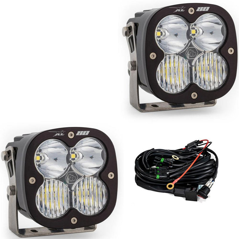 Baja Designs XL80 LED Auxiliary Light Pod Pair, whole product on a studio background: A pair of Baja Designs XL 80 pods with clear lenses shown on a white background beside the wiring harness