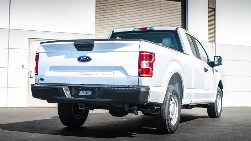Borla ATAK Cat-Back Exhaust System installed on a Ford F-150: A white Ford F-150 seen from the rear quarter in front of a building, with the Borla exhaust tips under the bumper