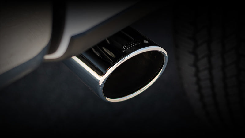 Close-up of the Borla ATAK Cat-Back Exhaust System: close view of a single polished Borla exhaust tip beside a truck tire on a dark background