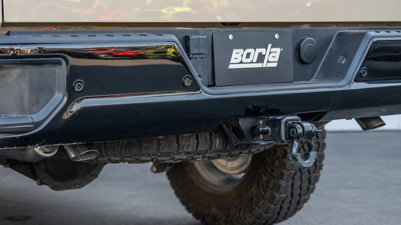 Borla ATAK Cat-Back Exhaust System on a vehicle: low view of a rear bumper with a Borla license plate and exhaust outlets below on a lifted truck