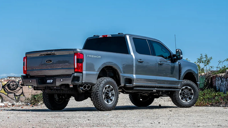 Borla S-Type Cat-Back Exhaust System installed on a Ford F-250 Super Duty Tremor: rear three-quarter view of a gray Ford Super Duty Tremor crew cab with dual exhaust tips under a blue sky