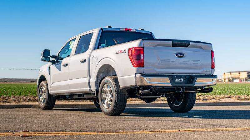Borla S-Type Cat-Back Exhaust System installed on a Ford F-150: rear three-quarter view of a white Ford F-150 4x4 with a Borla exhaust on a rural road